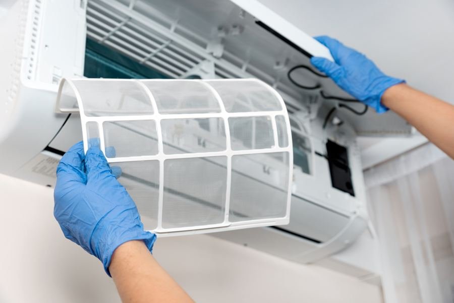 Técnico removendo o filtro de um ar-condicionado para limpeza