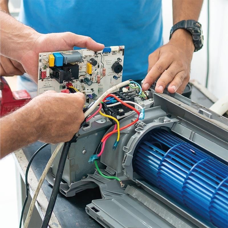 Técnico fazendo manutenção na placa eletrônica de um ar-condicionado